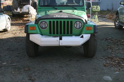 1987 Suzuki Samurai - Front view of a green Jeep Wrangler a custom white bumper and the Jeep logo.