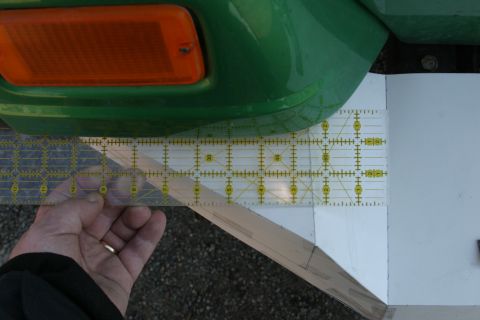 1987 Suzuki Samurai - A ruler is used to measure a part of a green vehicle bumper, near an orange marker light.