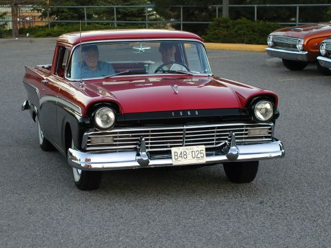 1967 Ford Ranchero - This 1957 Ford Ranchero is shown from the front with two people inside. A second vehicle is parked nearby.
