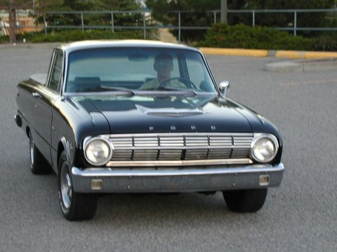 1967 Ford Ranchero - A black 1960 Ford Ranchero pickup truck is seen from the front, with a driver behind the wheel.