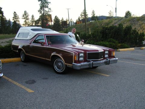 1967 Ford Ranchero - This Ford Ranchero is equipped with a camper shell and has a man standing next to it.