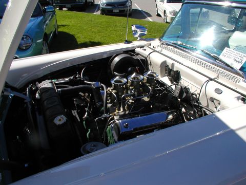 1967 Ford Ranchero - The engine bay of a classic car is shown, with a prominent V8 engine and multiple carburetors. Other vehicles are visible in the background.
