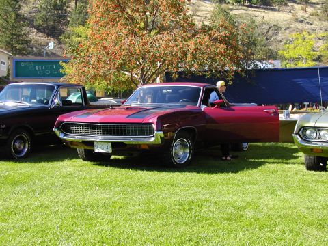 1967 Ford Ranchero - A red 1970 Ford Ranchero is parked on the grass with its driver's door open, alongside other vehicles.