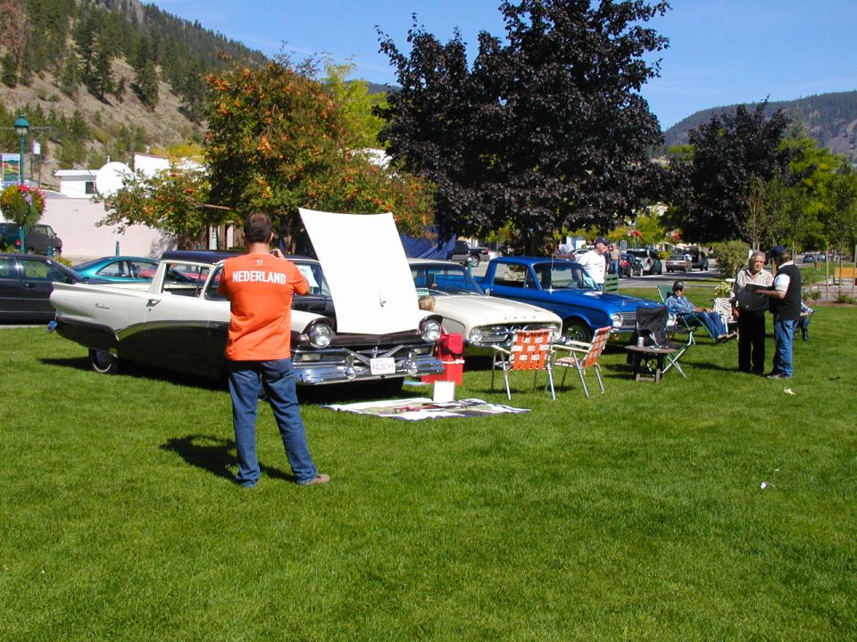 Vintage cars displayed on grass at outdoor car show with spectators