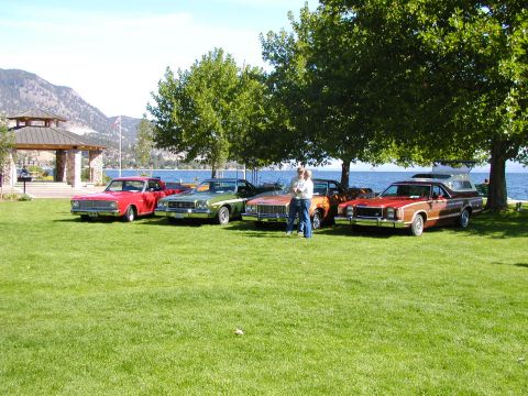 1967 Ford Ranchero - A lineup of four classic pickup trucks are parked on a lawn next to a body of water.