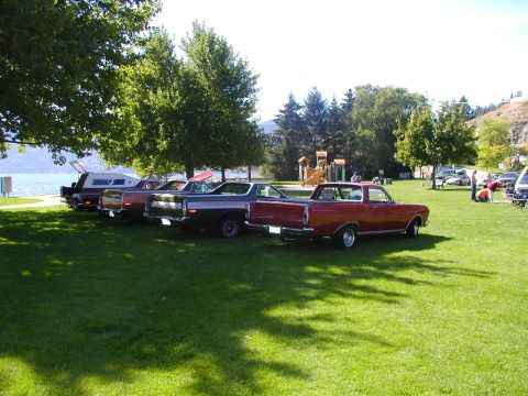 1967 Ford Ranchero - Several classic pickup trucks, including a 1967 Ford Ranchero, are parked on a grassy area near a body of water.