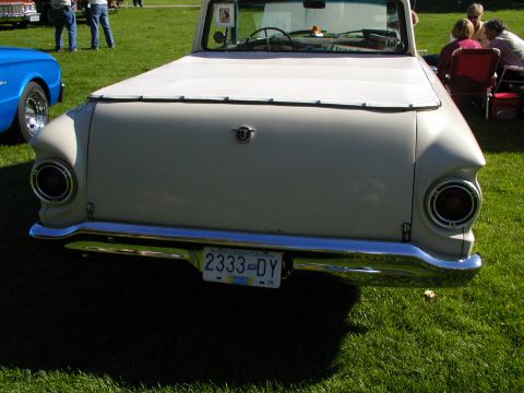 1967 Ford Ranchero - Rear view of a 1967 Ford Ranchero, its distinctive taillights and chrome bumper, parked on a grassy field.