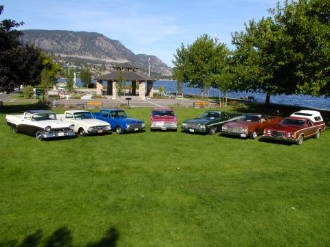 1967 Ford Ranchero - A collection of vintage cars displayed outdoors with a scenic lake and mountain backdrop.