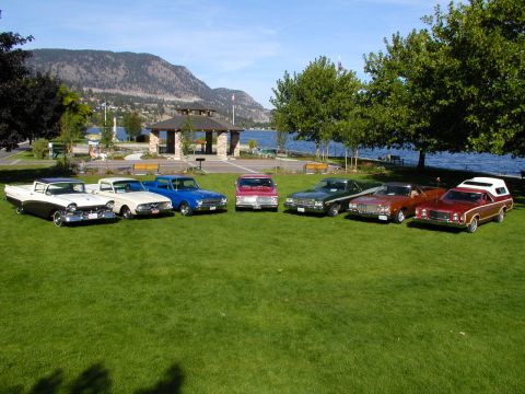 1967 Ford Ranchero - A collection of vintage vehicles are displayed on a sunny day with a scenic lake and mountain backdrop.