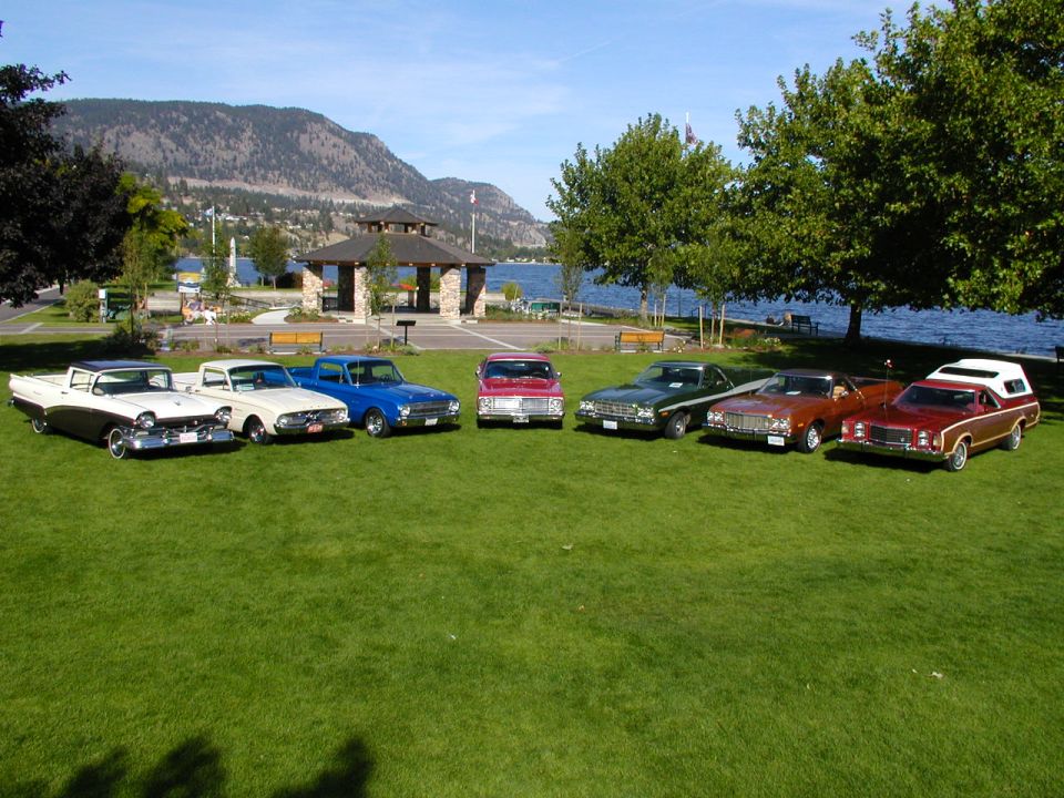 Eight Ford Rancheros of different generations lined up on a lakeside lawn