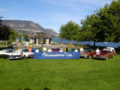 1967 Ford Ranchero - A group of Ford Rancheros and other vehicles are displayed at an outdoor event with a lake and mountains in the background.