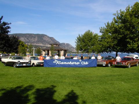 1967 Ford Ranchero - A collection of Ford Rancheros and other vehicles are displayed on a grassy area near a lake, with a banner identifying the 'Ranchero Club'.