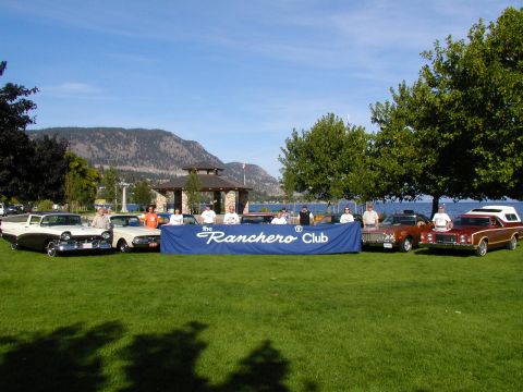 1967 Ford Ranchero - A group of people stand behind a banner at a Ranchero Club event, with several Ford Rancheros on display.