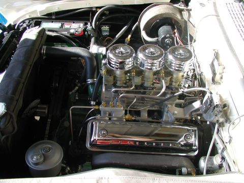 1967 Ford Ranchero - Close-up view of a V8 engine a triple carburetor setup and polished chrome valve covers.