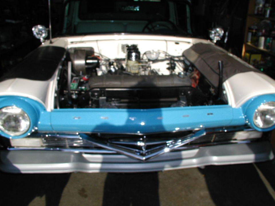 Turquoise and white 1950s Ford in garage, hood and fenders off exposing V8 and carburetor
