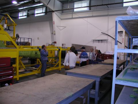 1967 Ford Ranchero - A group of people observe a large yellow assembly machine in a factory setting.