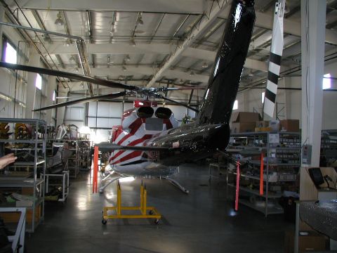 1967 Ford Ranchero - A helicopter is parked inside a workshop, with shelves of parts visible in the background.