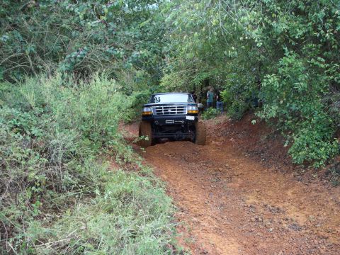 1995 Ford Bronco - A black 1995 Ford Bronco navigates a muddy, wooded trail.