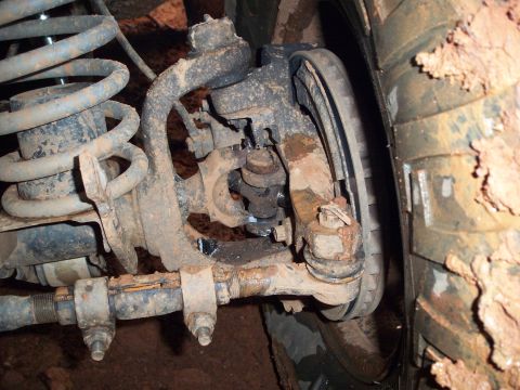 1995 Ford Bronco - Close-up view of the front suspension and tire, heavily coated in mud and rust. The Supermotors.net logo is visible in the lower right corn…