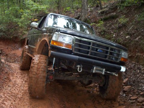 1995 Ford Bronco - Muddy 1995 Ford Bronco navigating a difficult off-road trail.
