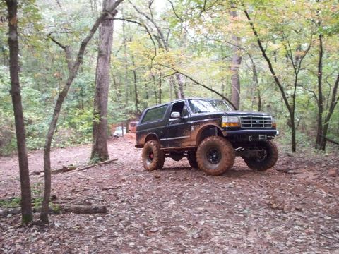 1995 Ford Bronco - This lifted 1995 Ford Bronco navigates a muddy, wooded path, its off-road capabilities.