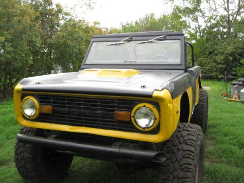 1973 Ford Bronco - A 1973 Ford Bronco with a custom hood scoop and large off-road tires sits in a grassy yard.