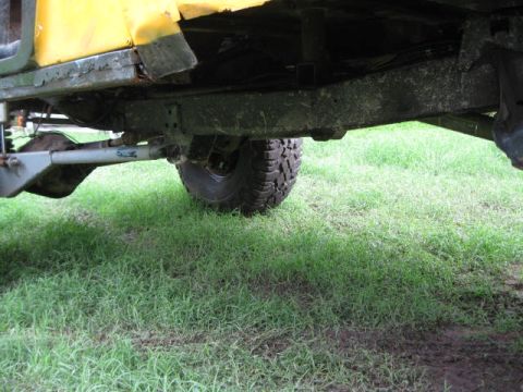 1973 Ford Bronco - The underside of a yellow vehicle shows its suspension and frame, with a "SUPERMOTORS" watermark visible.