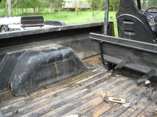 Rear cargo bed interior with wheel wells, seat, and roll bar. Supermotors.net logo visible