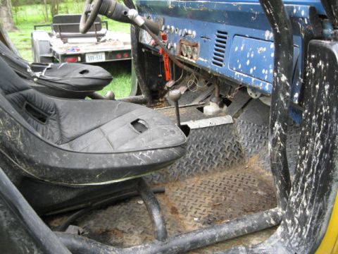 1973 Ford Bronco - The interior of a modified Ford Bronco, showing aftermarket seats and a roll cage. A trailer is parked behind it.