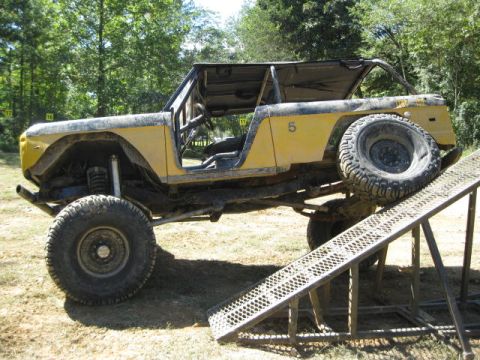 1973 Ford Bronco - Modified 1973 Ford Bronco with off-road tires is positioned on a metal ramp.