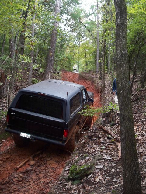 1995 Ford Bronco - This SUV navigates a challenging, wet, and wooded off-road path.