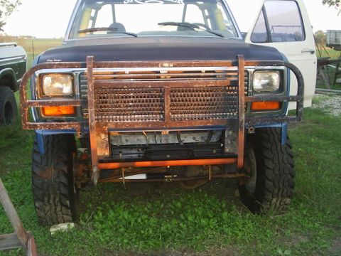 1984 Ford Bronco - This Ford Bronco features a heavy-duty brush guard and an aftermarket grille, with another vehicle visible to the side.