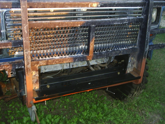 Front grille guard and frame of a blue full-size truck with a winch mount, at dusk