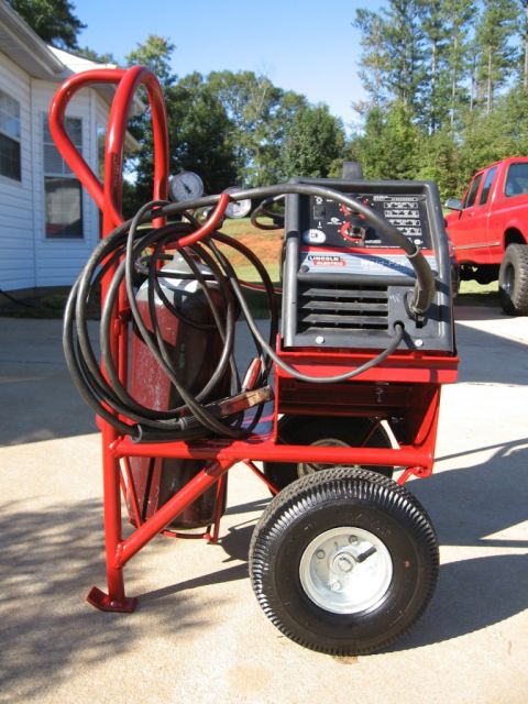 1995 Ford F-150 - Welding cart setup with a Lincoln Electric welder and gas cylinder, red pickup truck visible in background.