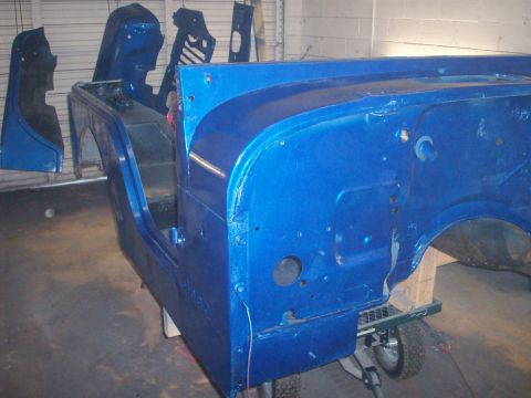1978 Jeep CJ5 - Disassembled blue Jeep CJ body parts are shown in a workshop, likely undergoing restoration.
