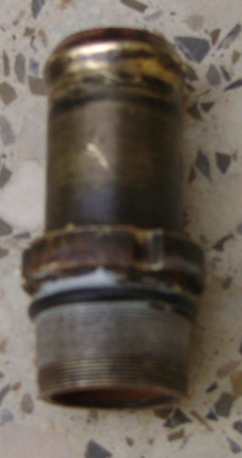 1998 Ford Crown Victoria - A metal pipe fitting with a threaded end and a brass-colored top is shown.