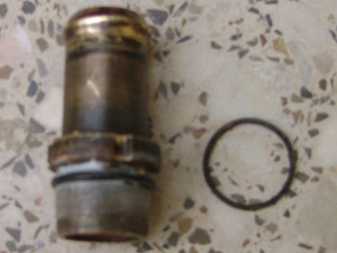 1998 Ford Crown Victoria - A metal thermostat housing and its o-ring are shown on a speckled surface, with a SuperMotors watermark visible.