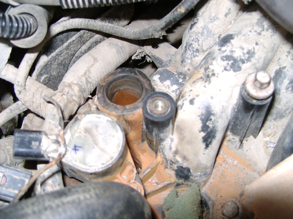 Engine intake manifold with dirt and grime, showing two circular openings and electrical connectors