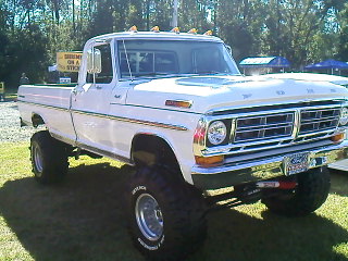 1990 Ford Bronco - This lifted white Ford pickup truck features a prominent grille and appears to be from the early 1970s.