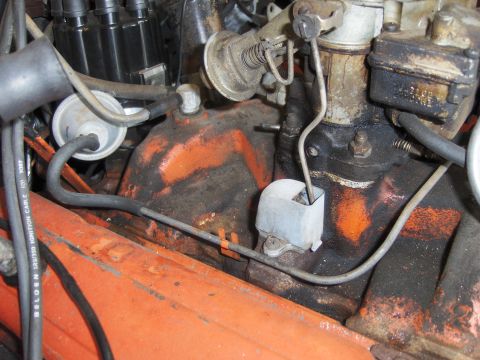 1971 Chevrolet Camaro - This image shows a close-up view of various engine parts, including a carburetor and distributor, with visible hoses and wiring.
