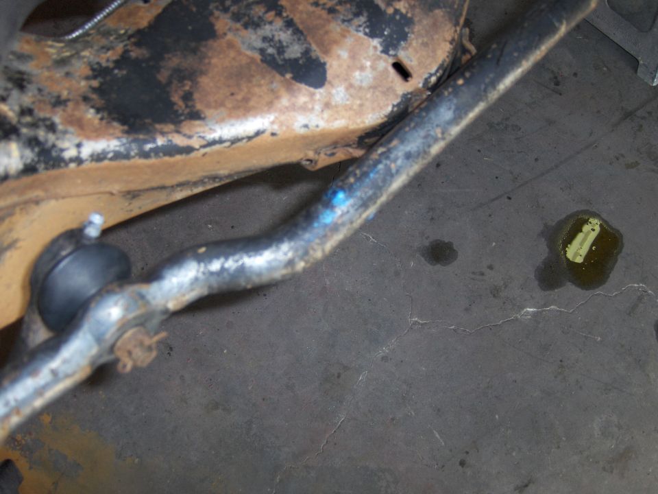 Close-up of a rusted vehicle suspension component with a ball joint and a blue mark