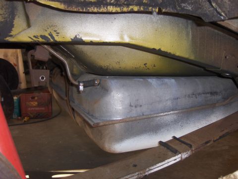 1971 Chevrolet Camaro - The underside of a vehicle shows the fuel tank and part of the suspension system, with a red crate in the background.