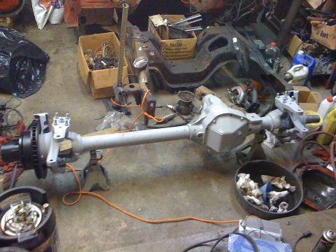 1978 Ford Bronco - A vehicle axle assembly is shown on jack stands in a cluttered garage environment.