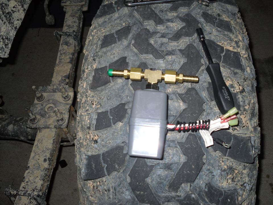 Close-up of a solenoid valve and brass fittings on a tire tread