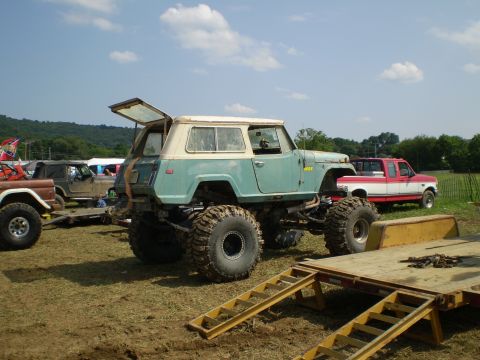 2005 Ford Excursion - Modified Jeep Commando with oversized tires parked outdoors next to a pickup truck.