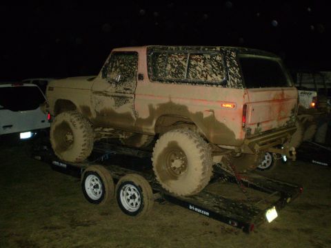 2005 Ford Excursion - A heavily mud-caked 1978 Ford Bronco is loaded onto a trailer at night.