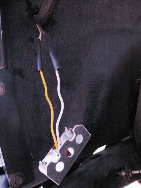 1986 Ford Bronco - This image shows a close-up view of a vehicle's wiring harness and a metal connector bracket.