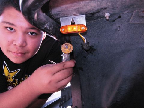 1986 Ford Bronco - A person holds a side marker light assembly, showing its wiring and mounting bracket.