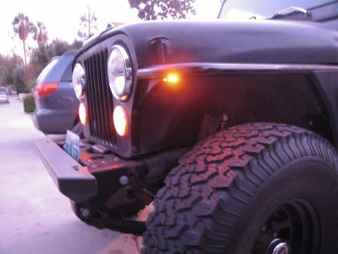 1986 Ford Bronco - Front corner view of a Jeep CJ showing its grille, headlights, and turn signal light.