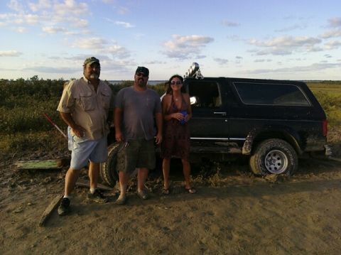 1993 Ford Bronco - A group poses with a black 1993 Ford Bronco that appears to be stuck in the mud.